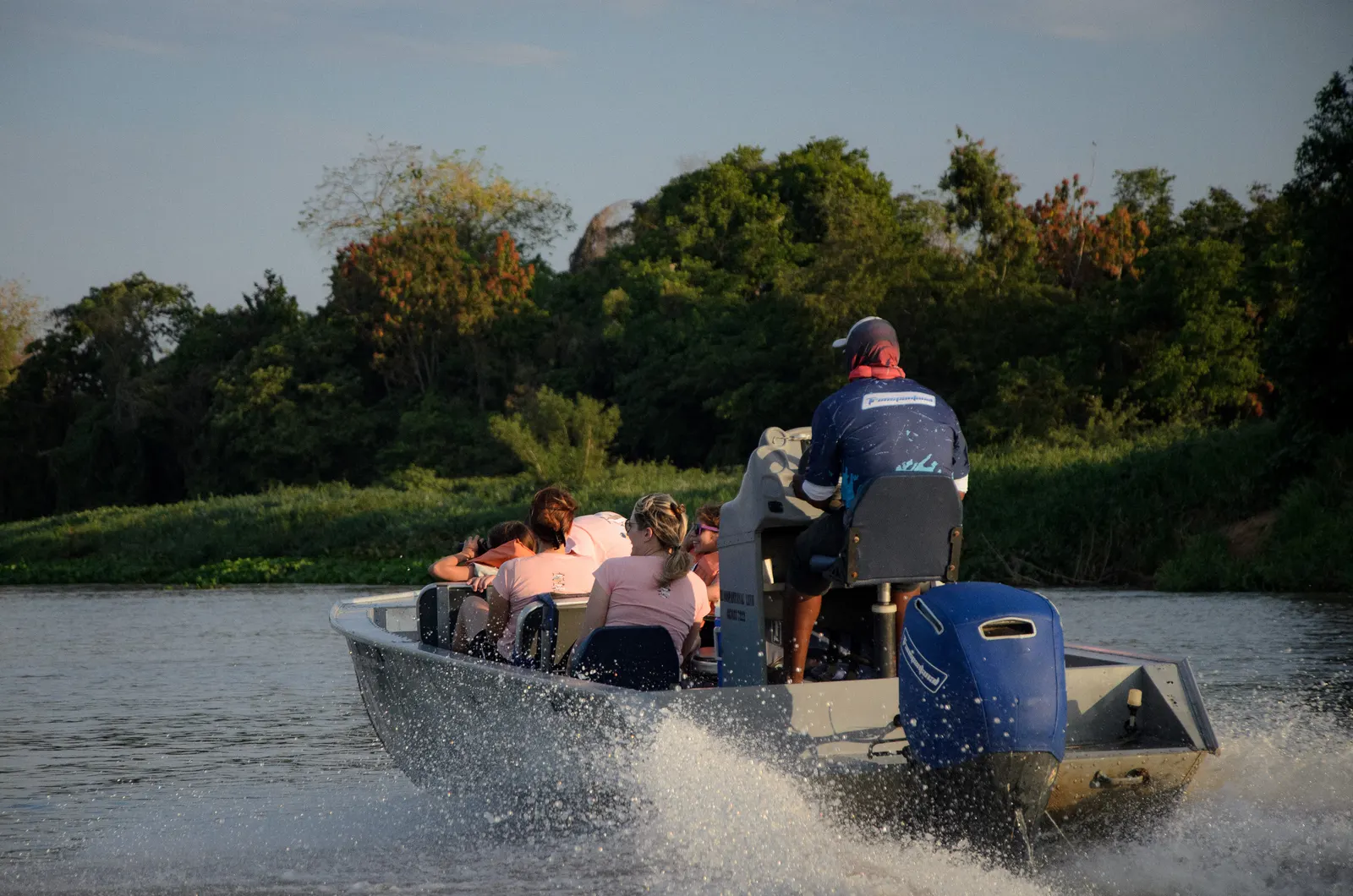 Grupo a bordo de uma lancha navegando ao entardecer