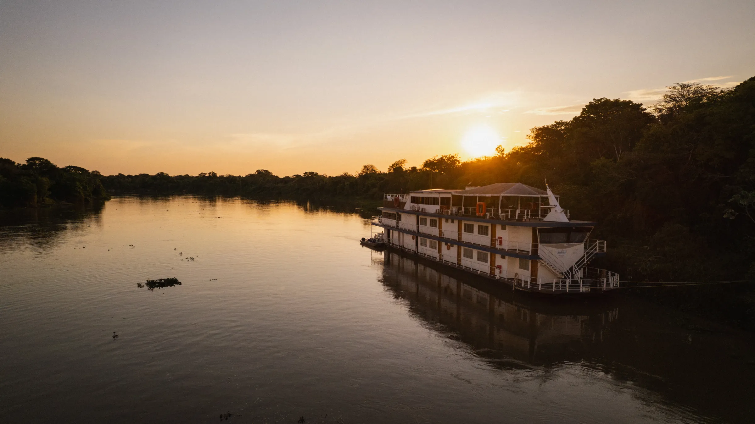 Barco navegando o rio do Pantanal ao pôr do sol